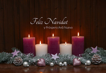 Velas encendidas con adornos navideños y ramas de abeto frente a una tabla de madera. En la madera está escrito en español el saludo «Feliz Navidad y Próspero Año Nuevo».