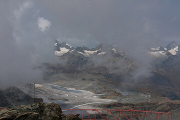 Cloudy day over the Swiss Alps, viewed from Glacier Paradise in Zermatt, with dramatic peaks and misty alpine scenery