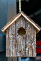 Rustic wooden birdhouse hanging outdoors in a natural setting with a simple design