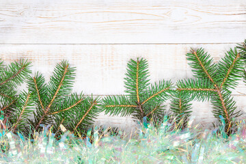 Christmas background - fir branches and bright tinsel over white wooden table