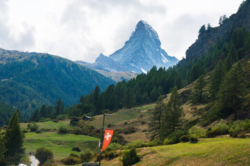 Matterhorn in green Swiss valley with a Gornera River flowing from the mountain with Swiss flag in Zermatt, Switzerland