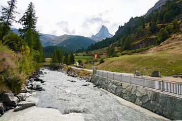 Matterhorn in green Swiss valley with a Gornera River flowing from the mountain with Swiss flag in Zermatt, Switzerland