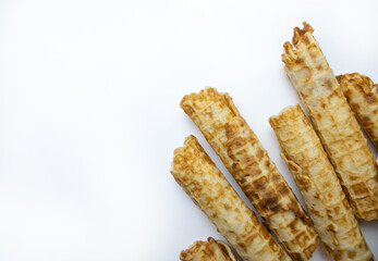 Crispy wafer sticks stacked in a corner on a clean white background.