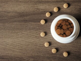 White bottle of brown pills on a wooden table