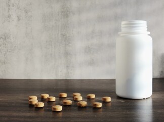 White bottle of brown pills on a wooden table