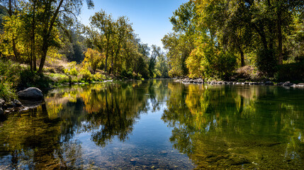 Serene river reflecting autumn trees under a clear blue sky