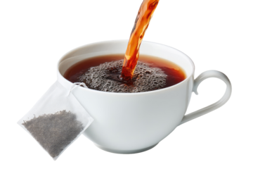 Hot tea being poured into a white mug.  A tea bag is beside the cup