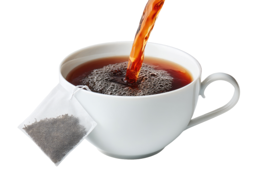 Hot tea being poured into a white mug.  A tea bag is beside the cup