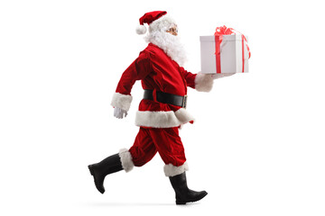 Full length profile shot of Santa Claus running with a gift box