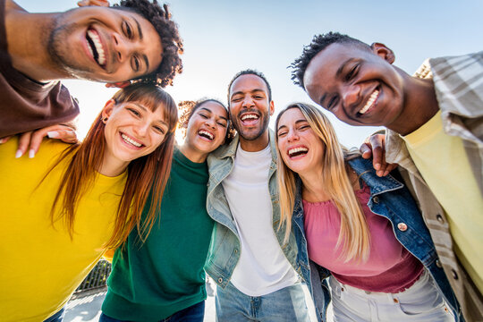 Happy multiracial friends having fun on city street - Group of young people smiling at camera outside - Friendship concept with guys and girls walking in downtown road