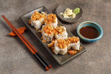 Crispy roll saumon avocat sur table foncée avec sauces soja, baguettes, vaisselle traditionnelle. Cuisine japonaise. 