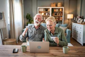 Senior couple enjoying online shopping using laptop and credit card