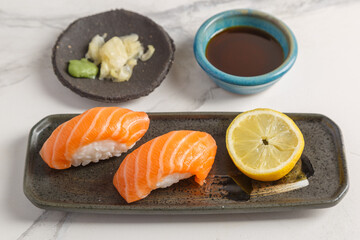 Sushi au saumon avec des baguettes et sauce soja sur un plat traditionnel, fond en marbre