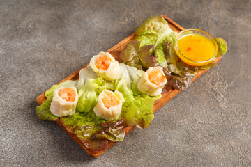 Vapeurs crevettes sur feuille de salade avec sauce aigre-douce sur table foncée