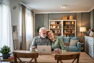Senior couple enjoying online shopping using laptop and credit card