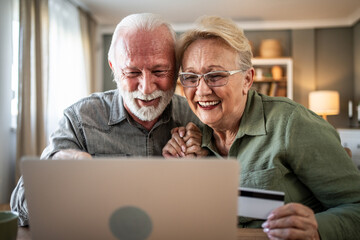 Happy senior couple enjoying online shopping at home