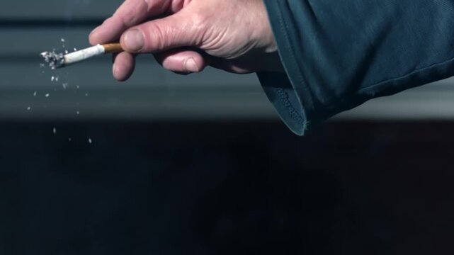 Hand flicking ash of cigarette 