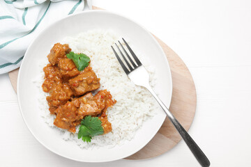 Delicious chicken tikka masala with rice, cilantro and fork on white wooden table, flat lay