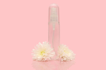 A transparent container with white flowers on a pink background. A bottle for liquid.
