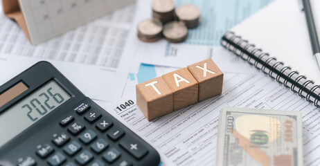 Tax planning concept for 2026. Wooden blocks with the word tax. Calculator on phone. Interest, Financial calculations, Tax law, Tax payment, Government taxes and budget planning.
