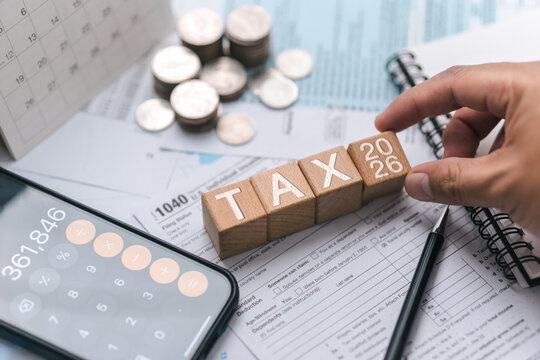 Tax planning concept for 2026. Wooden blocks with the word tax. Calculator on phone. Interest, Financial calculations, Tax law, Tax payment, Government taxes and budget planning.