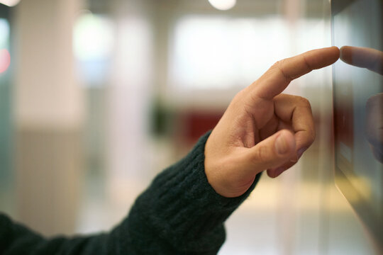 Caucasian young adult man hand interacting with touchscreen device in modern business environment, finger pressing digital interface, technology usage in professional setting