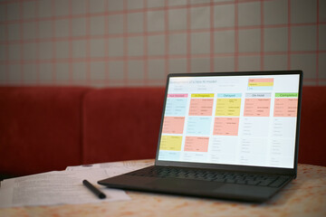Laptop displaying colorful project management dashboard with development stages for new AI model,...