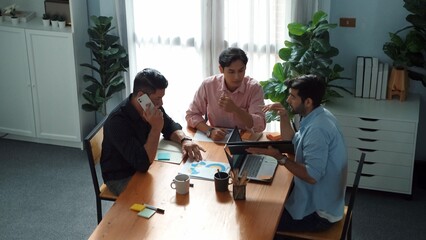 Top view of team working together to brainstorm idea while project manager talking to phone at meeting room. Male leader calling investor and present plan while team discussing strategy. Convocation.