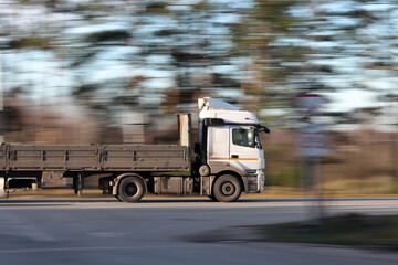 A truck tractor with a trailer is driving on the highway