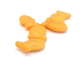 A scattering of yellow fish crackers on white background 