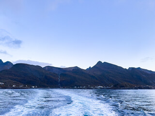 Ferry voyaging towards the stunning lofoten islands in norway, with the norwegian flag waving proudly
