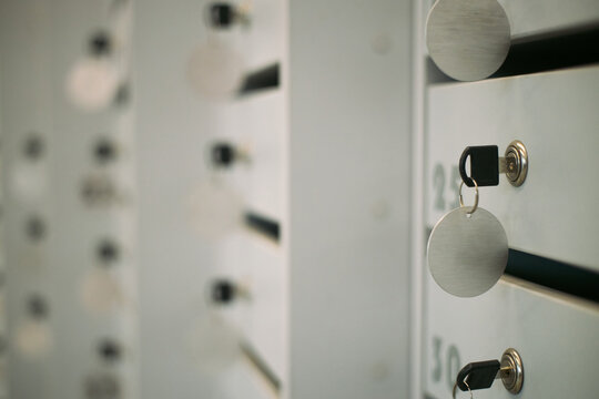 Closeup of metal key inserted into lock of numbered locker in business environment, showing secure storage solution with focus on key and lock mechanism, blurred background