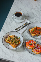 coffee with trio of gourmet toasts on marble table in hard light