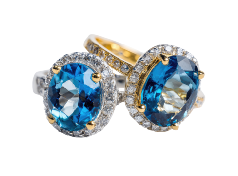 Close-up of two rings, featuring oval-shaped, vivid blue gemstones, set in gold and diamond halo settings