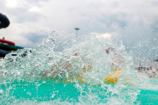 Joyful splashes fill the air as children dive into a sparkling blue pool at a lively water park. Families gather around, seeking fun and adventure in the summer sun