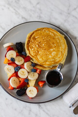 pancakes with fruit and maple syrup in hard light