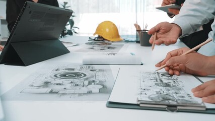 A dynamic scene of diverse professionals engaged in a creative discussion over technical drawings and designs in a modern workspace, showcasing collaboration and innovation. SACTR