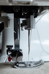 a side view of a sewing machine presser foot on fabric with beige thread visible in the needle