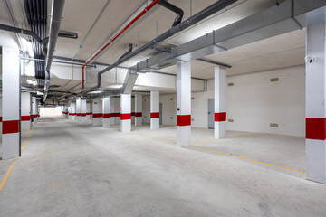 Obraz premium Modern underground parking area with ventilation pipes and marked parking spots