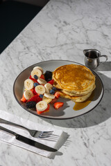 pancakes with fruit and maple syrup in hard light
