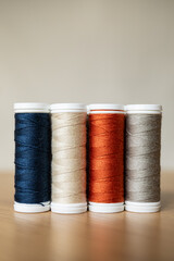 sewing thread spools in four different colors placed on a table with a light background