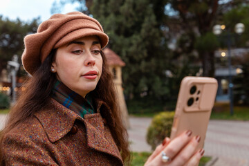 A peaceful moment in the city as a stylish woman in a beige coat scrolls through her smartphone and...