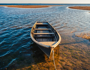 Obraz premium “Wooden Boat in Shallow Water During Golden Hour”