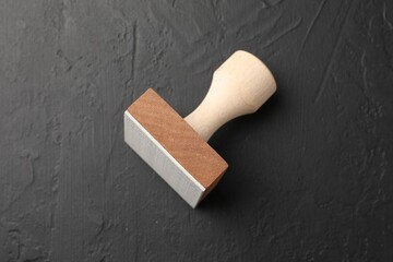 One wooden stamp on dark textured table, top view