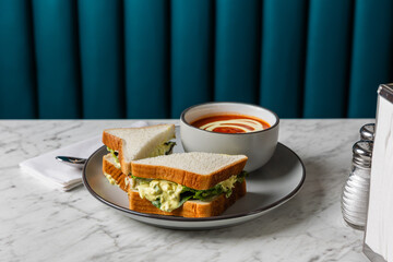 egg salad sandwich with tomato soup on marble table