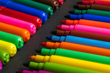 many colorful felt-tip pens on a black background