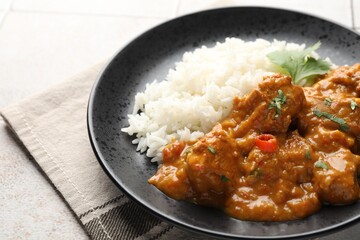 Chicken tikka masala with rice served on light tiled table, closeup
