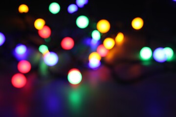 Bright Christmas lights in darkness, bokeh effect. New Year greeting card
