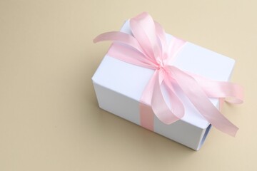 Beautiful gift box on beige background, closeup. Space for text