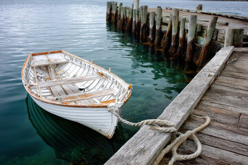 Old wooden boat moored by weathered dock at a tranquil waterfront location